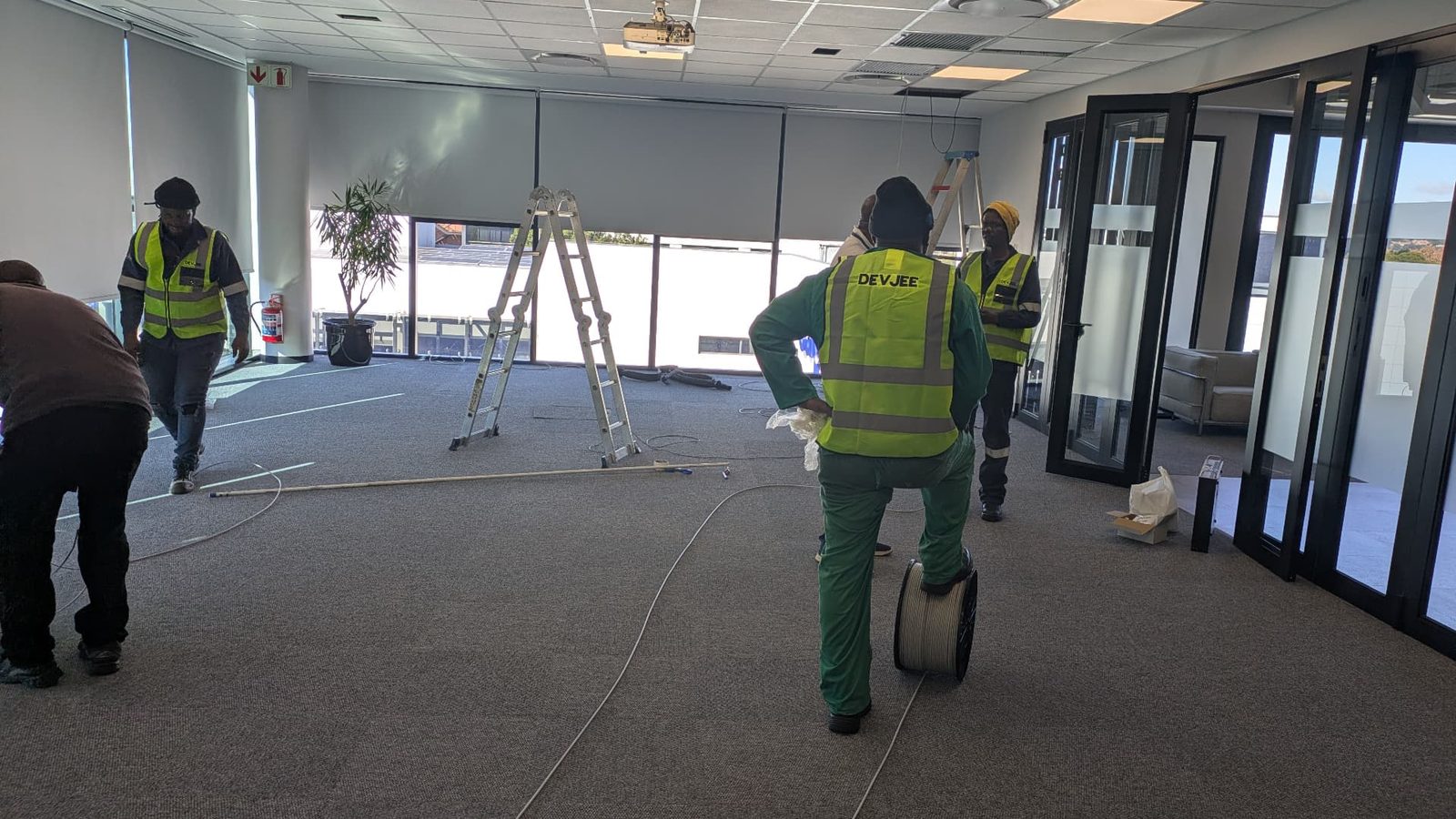 Devjee International field team carrying out ICT infrastructure installation work in a commercial office environment.